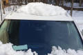 Упавшая со здания груда снега прогнула крышу припаркованной машины